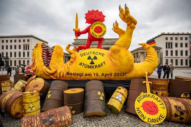 Greenpeace präsentiert AKW-Dinosaurier am Brandenburger Tor, Anlässlich der Abschaltung der letzten drei verbliebenen Atomkraftwerke (AKW) in Deutschland, präsentiert Greenpeace eine vier Meter hohe Skulptur eines erlegten Dinosauriers am Brandenburger Tor. Die Skulptur wurde von dem Düsseldorfer Bildhauer Jacques Tilly entworfen und gebaut. Der Saurier ist umgeben von Atommüllfässern, auf ihm steht als kämpferische Figur die Anti-Atomsonne in Siegerpose. Berlin Berlin Deutschland *** Greenpeace presents AKW dinosaur at the Brandenburg Gate, On the occasion of the shutdown of the last three remaining nuclear power plants AKW in Germany, Greenpeace presents a four-meter-high sculpture of a shot dinosaur at the Brandenburg Gate The