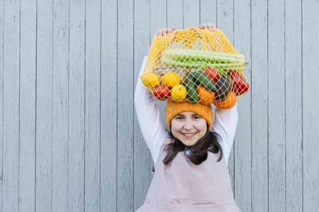 Happy girl carrying bag of groceries on head in front of wall model released, Symbolfoto, OSF01465