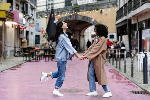 IMAGO Creative, Urban Lifestyle Cheerful friends holding hands and enjoying on footpath model released, Symbolfoto, JJF00594