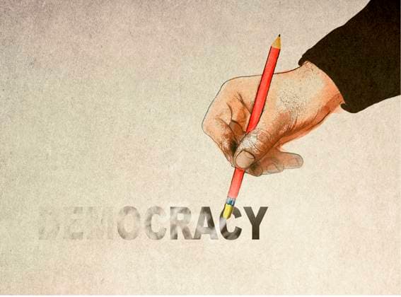 Hand holding pencil and erasing democracy text, GWAF00094