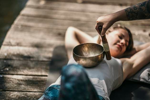 Therapist playing Tibetan singing bowl for customer lying down model released, Symbolfoto property released, MJRF00946