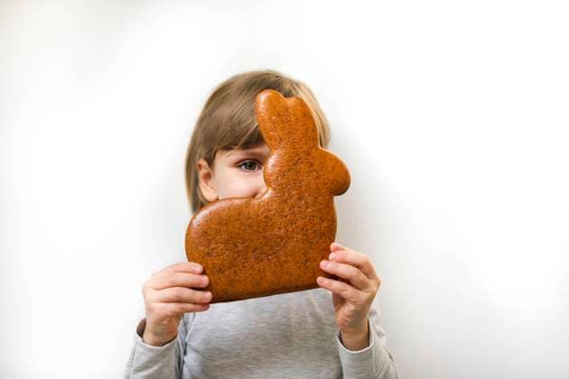 Girl with gingerbread Easter bunny covering face against white background model released, Symbolfoto, MOMF01009