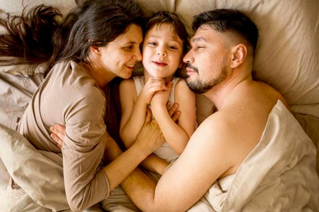 Happy parents lying with son on bed at home model released, Symbolfoto, ANAF01223