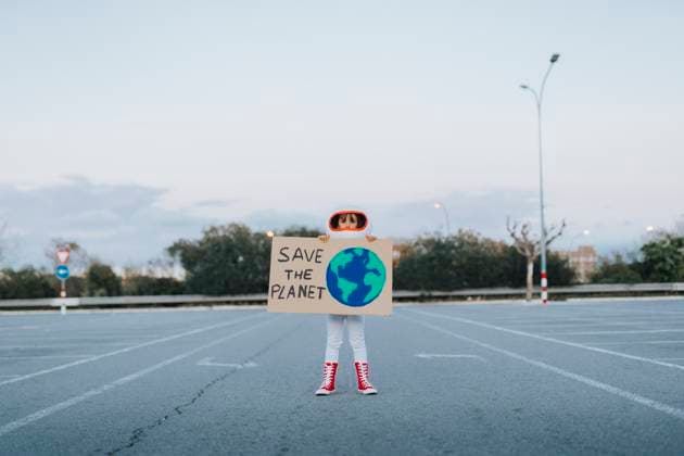 Girl dressed as astronaut showing Save The Planet cut out standing in parking lot model released, Symbolfoto property released, JCZF01241