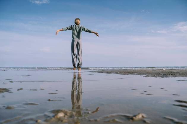 Carefree woman jumping with arms outstretched on shore at beach model released, Symbolfoto, NDEF00513