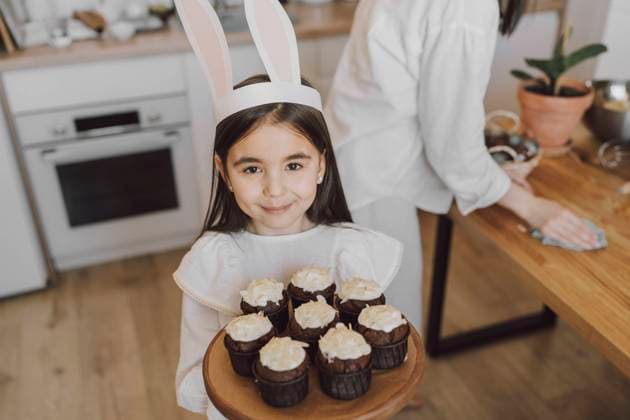 Smiling girl holding cupcakes on Easter day at home model released, Symbolfoto property released, VBUF00303