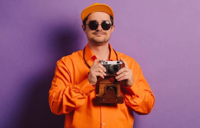 Man standing with retro style camera against purple background model released, Symbolfoto, VSNF00661