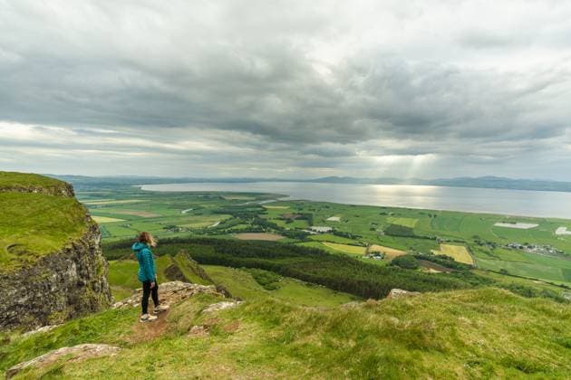 Creative Highlights Symbolbilder female standing in a green field with a beautiful view of the sea Buncrana, County Donegal, Ireland R_SIIZ230324M-1157296-01 ,model released, Symbolfoto