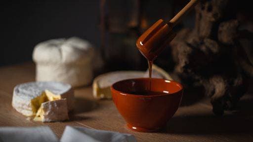 RECORD DATE NOT STATED A closeup of honey in a bowl and sliced camembert cheese on the table in the kitchen *** einer closeupe des Honig ÊIn einer Schüssel und aufgeschnittenen camembert Käse am der Tisch ÊIn der Küche 2660784