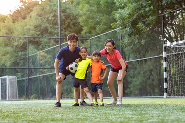 Happy young Chinese family playing football on soccer field Beijing China Copyright: xLanexOateyx bji06200133