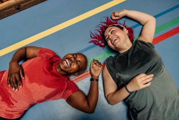 High angle view of female athletes laughing while lying on safety mat at sports court Sweden, Stockholm, model released Copyright: xMaskotx , MA100777 MA100777