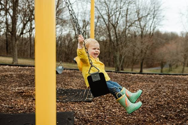 Creative Highlights Symbolbilder Happy child swinging in rain jacket and boots during spring Cape Girardeau, Missouri, United States CR_WEKW2303066F-1147040-01 ,model released, Symbolfoto