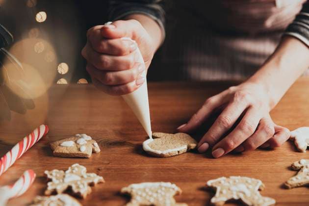 Christmas, New Year food preparation. Gingerbread cookies decorating with icing Christmas, New Year food preparation. Xmas gingerbread cooking, making and decorating freshly baked cookies. Closeup on cropped shot with woman hands holding icing and mastic, decorating cookies Copyright: xZoonar.com OlenaxIvanovax 19091120