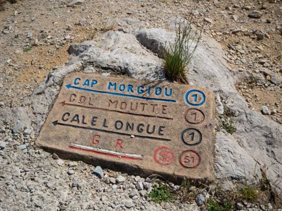 Marseille, France - May 20th 2022: A typical hiking sign on a rock in Calanques National Park. The Calanques National Park close to Marseille, France, offers spectacular hiking opportunities. A hiking sign showing the direction towards rocky bays. Copyright: xZoonar.com ThomasxStoiberx 19242797