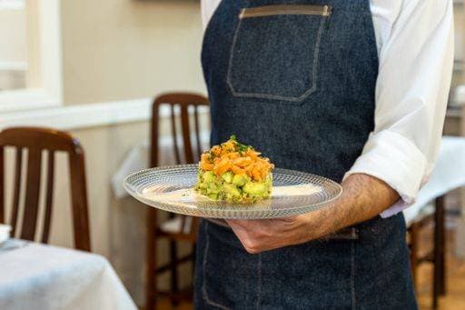RECORD DATE NOT STATED A waiter holding a plate with a salmon tartare with avocado and mango on it *** einer Kellner haltend einer Teller mit einer Lachs tartare mit avocado und mango am es 4940430
