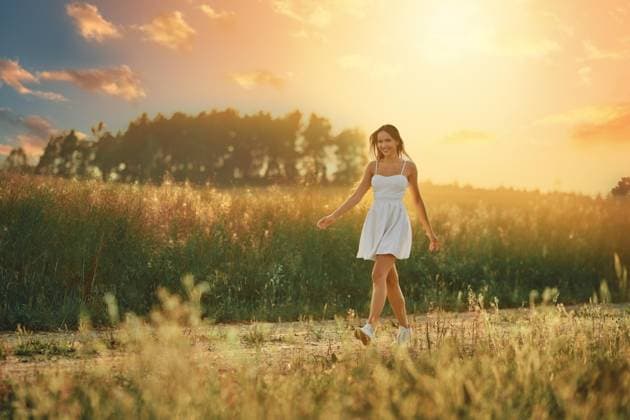 IMAGO Creative: Sommer, Abendspaziergang Glückliche junge Frau, die bei Sonnenuntergang auf einer Wiese entlang der Landstraße spaziert *** Happy Boy Woman, the at Sunset at a Meadow along the Country road walked Copyright: imageBROKER AlekseixIsachenko ibxaii08566090.jpg ,model released, Symbolfoto ,property released