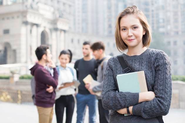 Cheerful female abroad student on campus with her friends in background Beijing China Copyright: xLianxFeix bji05160142