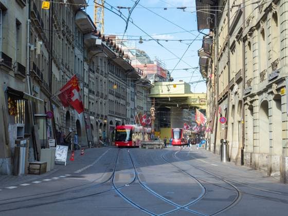 Berne, Switzerland - April 16th 2022: View along Marktgasse, a historic street in the city centre. Situation in the historic city centre of Berne, Switzerland. A tramcar and a trolley bus moving along a street with old buildings. Copyright: xZoonar.com ThomasxStoiberx 19927674