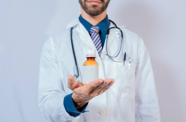 Die Hand des Arztes hält eine Flasche mit Sirup. Arzt zeigt eine Flasche mit Sirup *** the Hand of Doctor holds a Bottle with Syrup Doctor shows a Bottle with Syrup Copyright: imageBROKER/IsaixHernandez ibxiih09285864.jpg ,model released, Symbolfoto ,property released