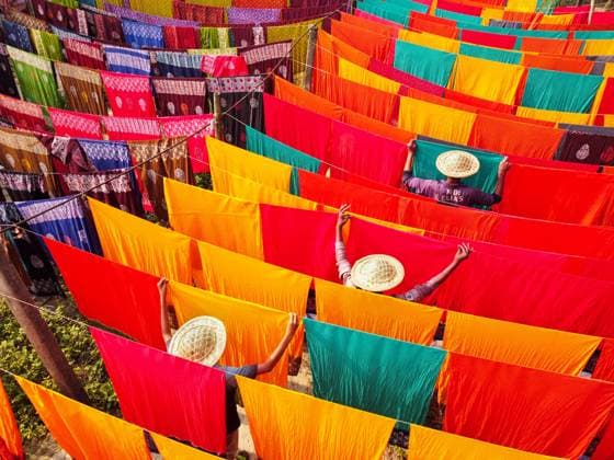 Bilder des Jahres 2023, News 05 Mai News Themen der Woche KW21 May 23, 2023, Narayanganj, Dhaka, Bangladesh: Workers hang hundreds of color-dyed sheets of cloth on a bamboo framework to dry in a dyeing factory in Narayanganj, Bangladesh. The drying process usually takes 4 hours, with each set of 200 pieces at a time to dry in temperatures over 42 degrees Celsius. Workers use hats for protection from the scorching heat because they have to constantly turn the colorful fabrics so that they dry perfectly in the sunlight. Narayanganj Bangladesh - ZUMAs231 20230523_zip_s231_015 Copyright: xJoyxSahax