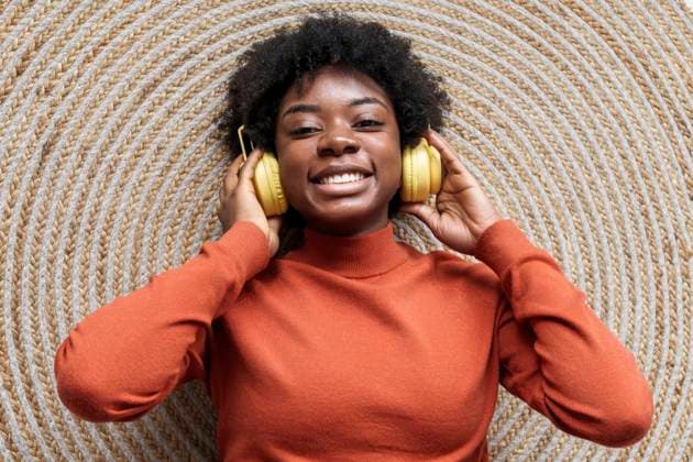Smiling young woman lying on rug and listening to music through wireless headphones model released, Symbolfoto property released, AAZF00395