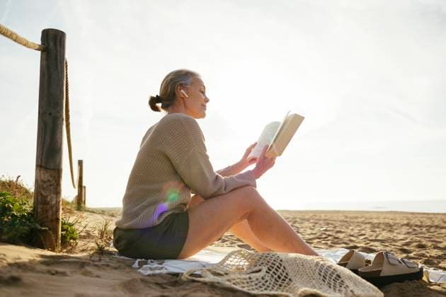Mature woman reading book on sunny day at beach model released, Symbolfoto, EBSF03213