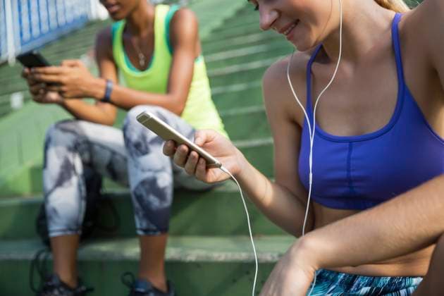 Smiling woman listening music with wired headphones through smart phone model released, Symbolfoto, IKF00448