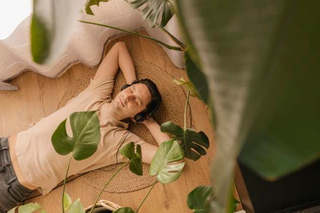 Man enjoying music through headphones lying with eyes closed on floor at home model released, Symbolfoto property released, VIVF00876