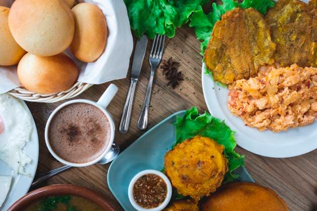 Top view of set of appetizing Colombian dishes with papas rellenas pan de bono chicharron bunuelos and caldo de costilla with various beverages served on wooden table in restaurant JordiCalvera_ID13995_422114_005 Copyright: xJordixCalverax RECORD DATE NOT STATED Model Released