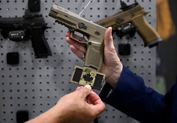 June 1, 2023, Ottawa, ON, CAN: A vendor compares the colour of a Canadian flag patch featuring the modern CADPAT camouflage design with a SIG Sauer P320, also known as the C22, that will be the new pistol for the Canadian Forces, at the CANSEC trade show, in Ottawa, on Thursday, June 1, 2023. Ottawa CAN - ZUMAc35_ 20230601_zaf_c35_071 Copyright: xJustinxTangx