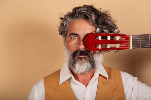 A closeup portrait of a bearded man covering his eye with a Spanish guitar on a yellow background *** einer closeupe Porträt des einer baertig Mann deckend seinem Auge mit einer spanisch Gitarre am einer Gelb Hintergrund 8903703 ,model released, Symbolfoto RECORD DATE NOT STATED