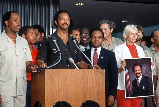 June 28, 1984, Dulles, VIrginia, US: The Reverend Jesse Jackson flanked by DC Mayor Marion Barry (L) and Delegate Walter Faunroy (D-DC) (R) Frances (Sissy) Farenthold (holding portrait of Jackson ) speaking at news conference inside Dulles International Airport shortly after landing on his return from Havana, Cuba with freed American and Cuban prisoners said that he was convinced peace was possible in Central America. Dulles US - ZUMAr142 19840628_zap_r142_005 Copyright: xMarkxReinsteinx