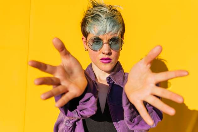 Woman wearing sunglasses showing palms in front of yellow wall model released, Symbolfoto, MGRF01004