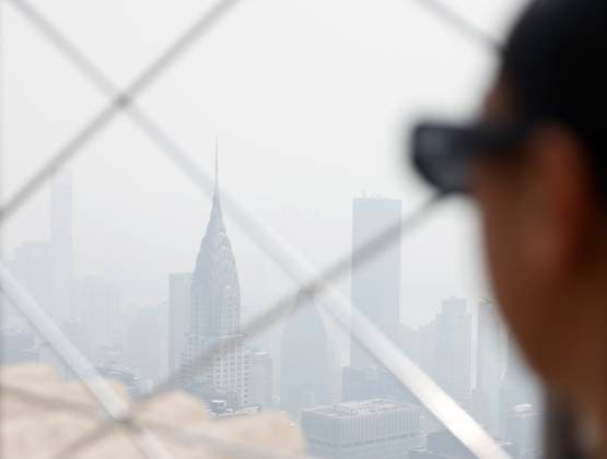 Tourists visit the observation deck of the Empire State Building as haze and smoke due to on going wildfires in Canada shroud the views of the Chrysler Building and the Manhattan skyline on Friday, June 30, 2023 in New York City.  NYP20230630115 JohnxAngelillo