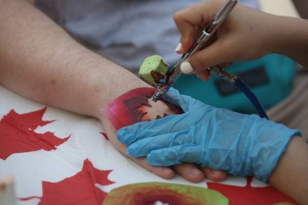 Canadians Celebrate Canada Day In Toronto Woman airbrushes a maple leaf on the hand of a man at a temporary tattoo station as Toronto Canada  Copyright: xCreativexTouchxImagingxLtdx originalFilename: friedman-canadian230701_nphQc.jpg