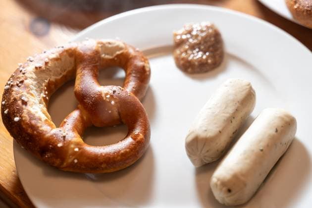 Augsburg, Bavaria, Germany - 2 July 2023: Bavarian vegan white sausage on a table for breakfast with pretzel and sweet mustard *** bayerische vegane Weißwurst auf einem Tisch zum Frühstück mit Breze und süßem Senf