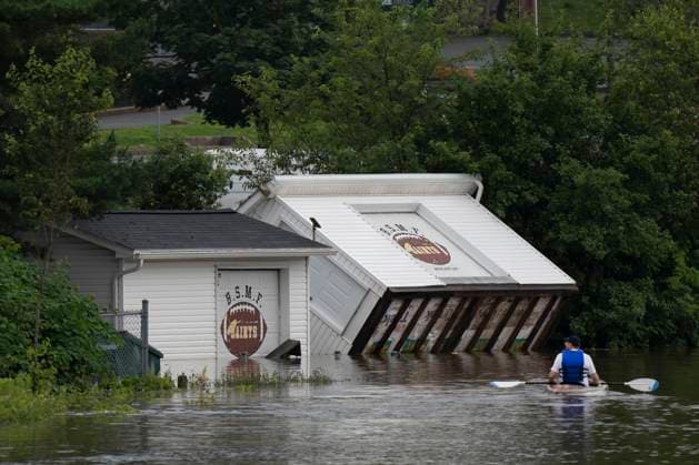 News Bilder des Tages July 22, 2023, Halifax, NS, Canada: Buildings are seen upended on a riverbank as a man paddles a kayak through floodwater following a major rain event in Halifax on Saturday, July 22, 2023. A long procession of intense thunderstorms have dumped record amounts of rain across a wide swath of Nova Scotia, causing flash flooding, road washouts and power outages. Halifax Canada  - ZUMAc35_ 20230722_zaf_c35_025 Copyright: xDarrenxCalabresex