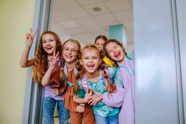 Smiling schoolgirls gesturing in classroom doorway model released, Symbolfoto property released, MDOF01395