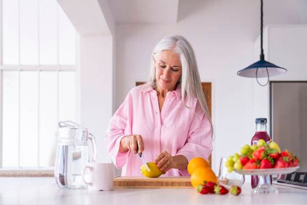 Mature woman cutting lemon in kitchen at home model released, Symbolfoto property released, OIPF03314