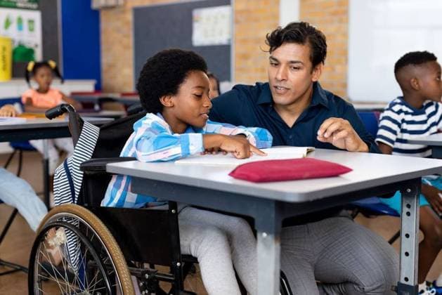Biracial male teacher helping schoolboy sitting in wheelchair in classroom at elementary school Biracial male teacher helping schoolboy sitting in wheelchair in classroom at elementary school. Disability, education, childhood, development, learning and elementary school, unaltered., model released, , property released, Cape Town, South Africa, 01.04.2023, 4070184.jpg, people,biracial,male,teacher,helping,schoolboy,sitting,wheelchair,classroom,elementary school,disability,education,childhood development,learning,unaltered,school,disabled,student,class,lesson,study,studying,knowledge,handicapped,handicap,college,university,elementary,teaching,learn,pupil,book,invalid,childhood,homework,development Child,Girl,Female,Multiracial,Boy,Male,Black