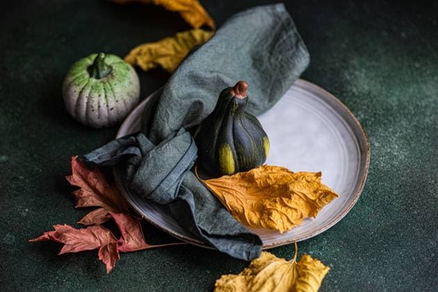 High angle of autumnal table setting with napkin, leaves and pumpkins placed on plate against dark surface Model Released AnnaBogush_ID15974_486383_003 Copyright: xAnnaxBogushx