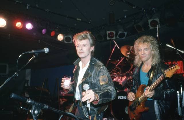 David Bowie performing on stage with drink in hand, wearing a black leather jacket, with Peter Frampton on guitar, New york, 1980s. Photo: Oscar Abolafia Everett Collection (davidbowie010)OSAB001 J4861 PUBLICATIONXNOTxINxCANxCHNxFRAxITAxJPNxNORxPOLxRUSxESPxUKxUSA Copyright: xx OSAB001 J4861 OSAB001_J4861_H