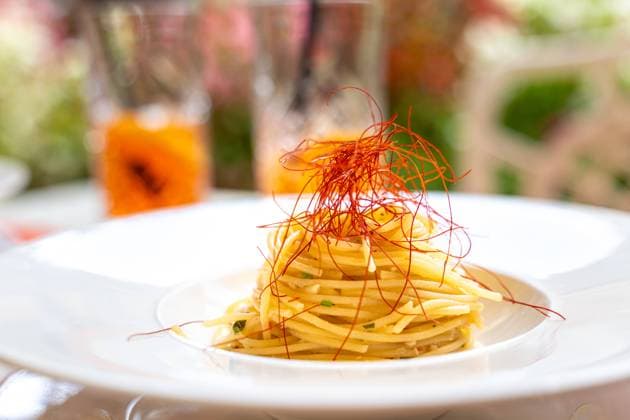 Limone, Lake Garda, Italy - 6 August 2023: Spaghetti aglio e olio on a white plate in a restaurant with saffron threads. Italian dish *** Spaghetti aglio e olio auf einem weißten Teller in einem Restaurant mit Safran Fäden. Italienisches Gericht