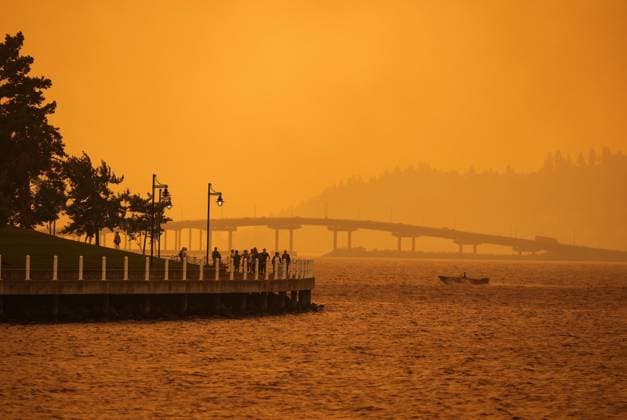 August 18, 2023, KELOWNA, BC, CANADA: A person travels in a boat past people walking on the boardwalk as smoke from the McDougall Creek wildfire blankets the area on Okanagan Lake, in Kelowna, B.C., Friday, Aug. 18, 2023. KELOWNA CANADA  - ZUMAc35_ 20230818_zaf_c35_050 Copyright: xDarrylxDyckx