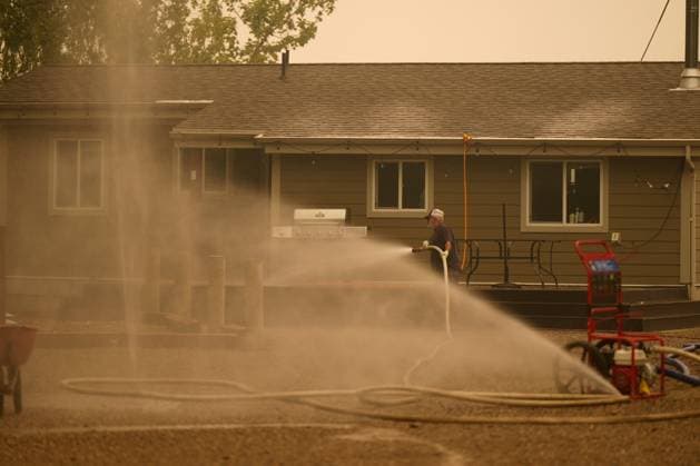 August 20, 2023, SCOTCH CREEK, BC, CANADA: Smoke fills the air as Trevor Manzuik showers his property in water after having been given a boat ride by a good samaritan, in Scotch Creek, B.C., Sunday, Aug. 20, 2023. Manzuik and his wife Pat were evacuated from the site due to the Lower East Adams Lake wildfire. SCOTCH CREEK CANADA  - ZUMAc35_ 20230820_zaf_c35_020 Copyright: xDarrylxDyckx