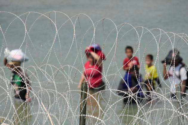 USA, Migranten aus Mittelamerika am Rio Grande in Eagle Pass, Texas August 21, 2023, Eagle Pass, TX, United States: A group of migrants look for an opening in the concertina wire barrier south of Eagle Pass where a 1000-foot string of buoys has been placed in the river to deter crossing the Rio Grande River into Texas. The migrants later found an opening and crossed into the United States as several U.S. governors were touring overhead by helicopter. Eagle Pass United States - ZUMAd150 20230821_znp_d150_010 Copyright: xBobxDaemmrichx