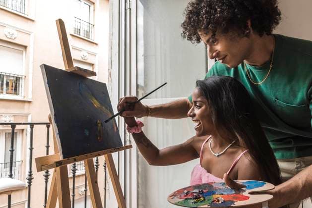 Smiling boyfriend helping girlfriend painting on canvas at home model released, Symbolfoto property released, PBTF00076
