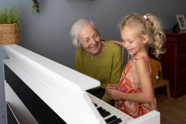 Smiling grandmother playing piano with granddaughter at home model released, Symbolfoto property released, SVKF01576