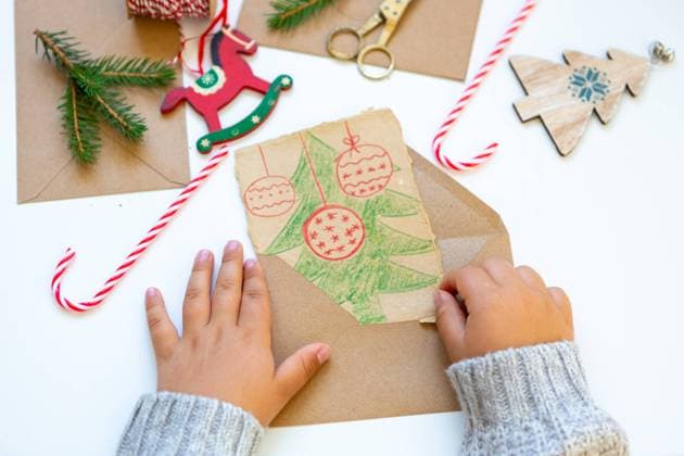 11 August 2023: Child making a self painted greeting card for Christmas. Hand of a young paints a card with a Christmas tree. Christmas greeting concept *** Kind bastelt eine selbstgemalte Grußkarte zu Weihnachten. Hand von einem jungen malt eine Karte mit einem Weihnachtsbaum. Weihnachtsgruß Konzept