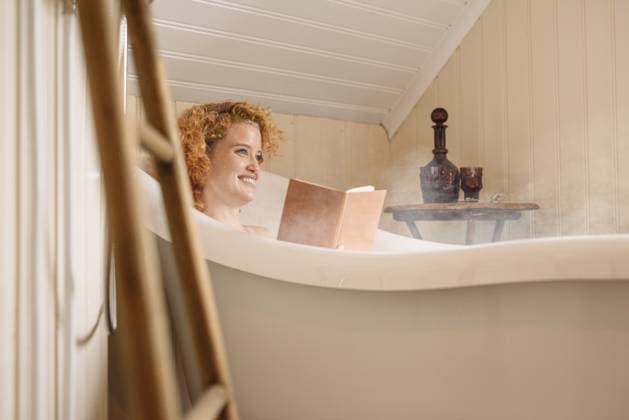 Cheerful young woman lying in bathtub and reading book in daylight Hveragerði, Iceland CR_OSBJ230828-1242950-01 ,model released, Symbolfoto ,property released